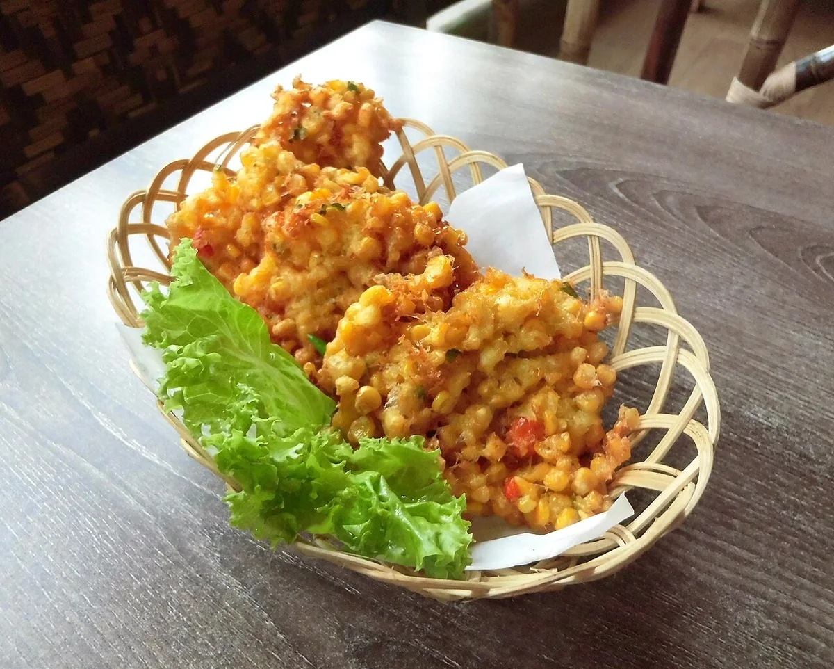Illustrative bakwan jagung, golden Indonesian sweetcorn fritters in a woven basket
