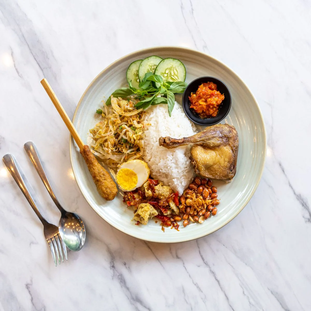 Illustrative nasi campur with rice, chicken, vegetables and sambal
